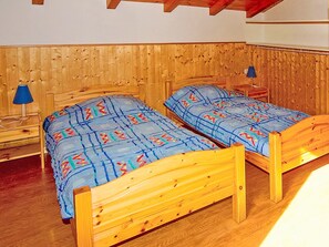 A room with two wooden beds, a nightstand with a lamp, and a wooden wall. - Flocon de Belleville by Interhome (Les Granges)