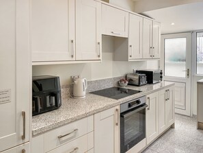 Eine moderne Küche mit weißen Schränken, einer Granit Arbeitsplatte, einer Kaffeemaschine, einem Toaster und einem Backofen.
