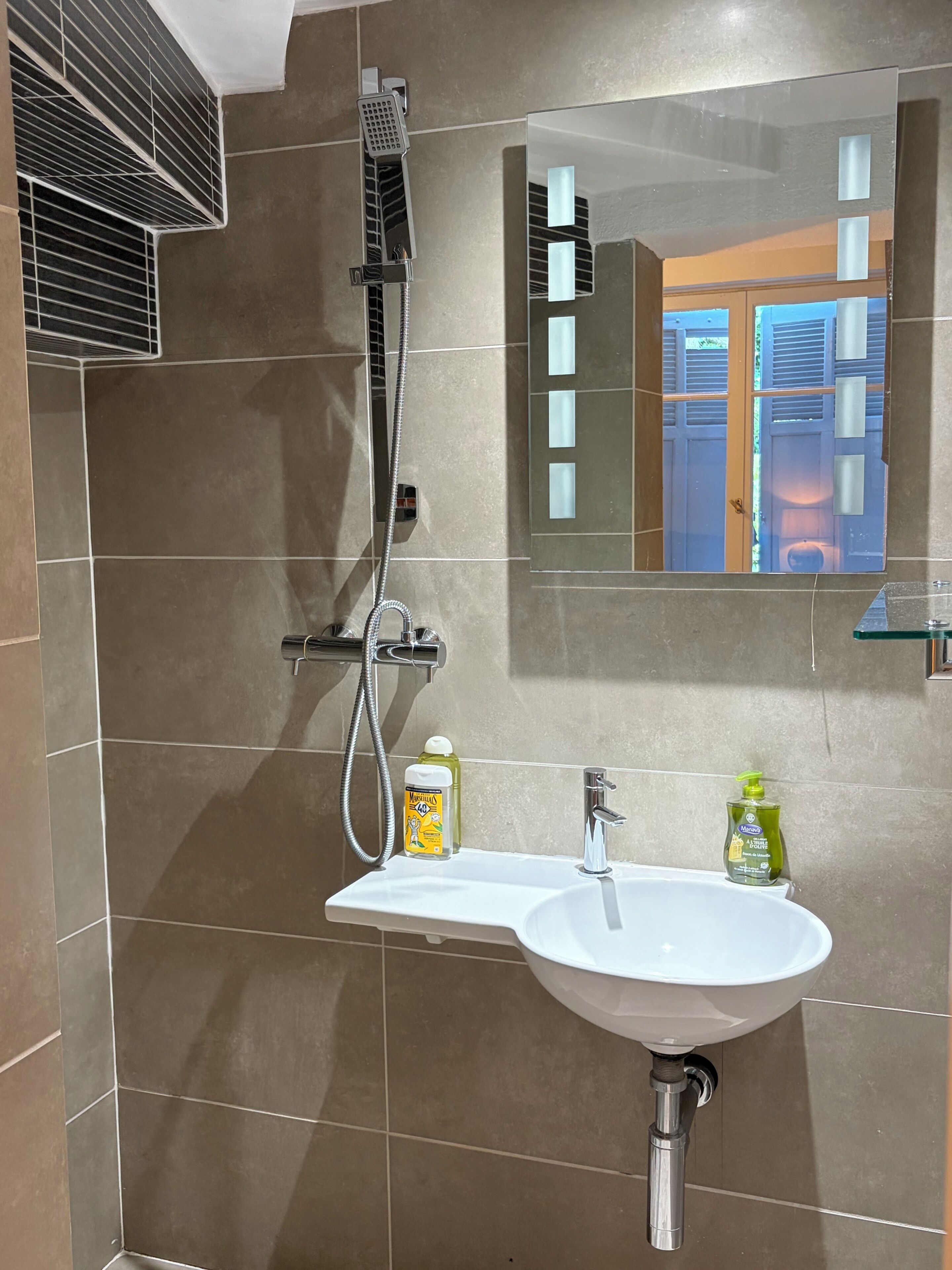 A bathroom with a shower, a sink, and a mirror.