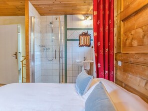 Ein holzgetäfeltes Zimmer im Blockhausstil mit einem Bett, einer Dusche und einem Badezimmer.