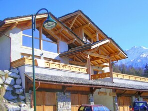Un chalet de montagne à la façade en pierre, doté de balcons en bois et d’une enseigne indiquant la présence d’un restaurant.