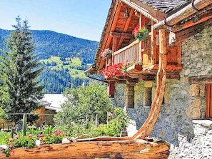 A traditional wooden chalet with a balcony, surrounded by lush greenery and a mountainous backdrop. - Chalet Coeur Paradis by Interhome (Peisey-Nancroix)