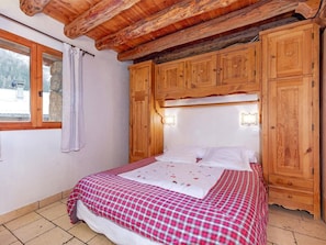 A bedroom with a bed, wooden headboard, and a window with curtains. - Chalet Coeur Paradis by Interhome (Peisey-Nancroix)