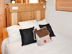 Ein Bett mit weißer Bettwäsche und mehreren Kissen, darunter ein Herzförmiges.