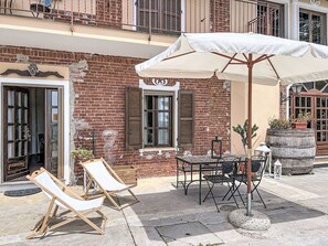 Un bâtiment en briques doté d’un balcon, d’une table avec des chaises et d’un grand parasol.