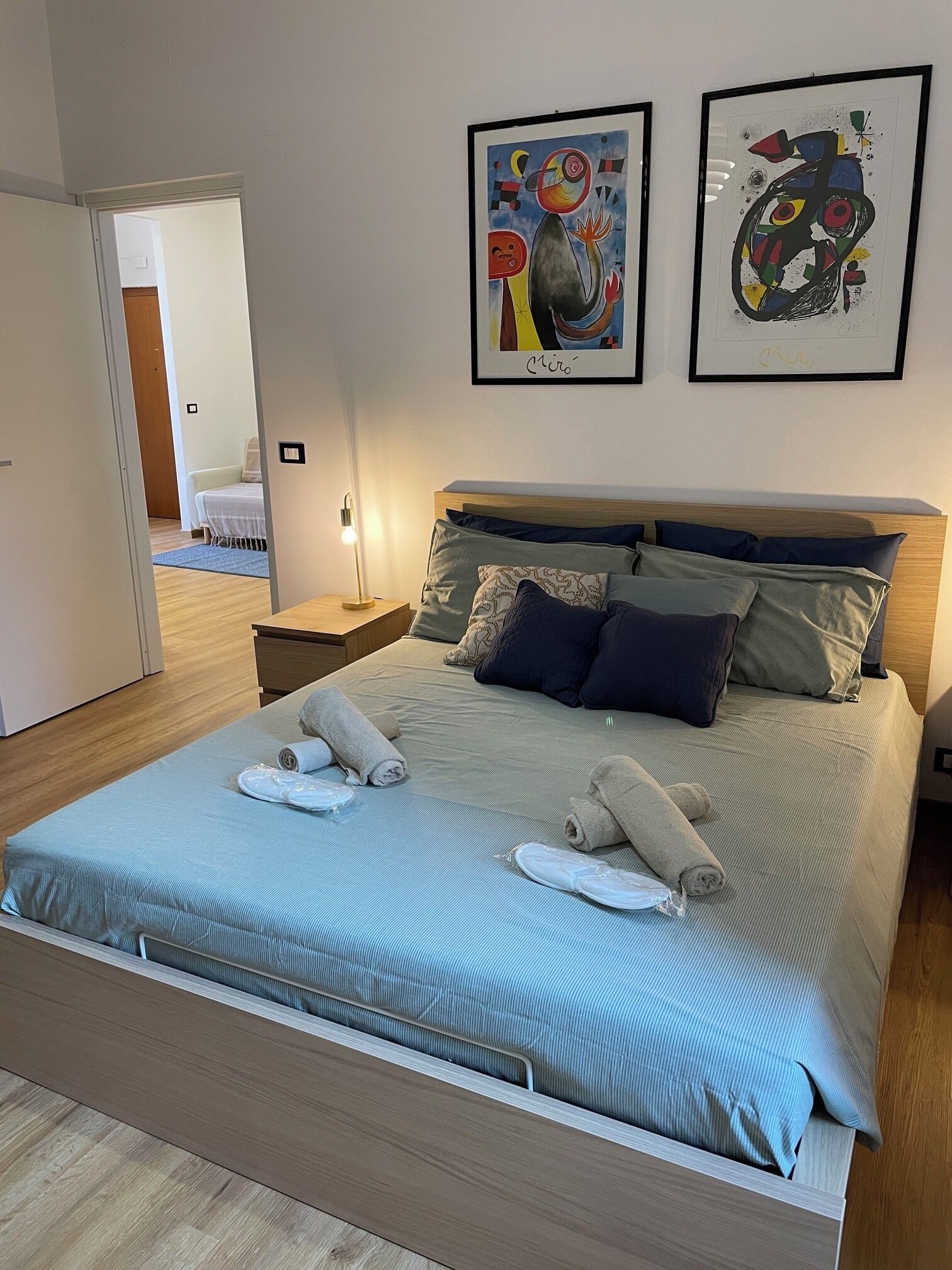 A neatly made bed with a blue striped bedspread, two pillows, and rolled towels. There are two framed artworks on the wall above the bed.