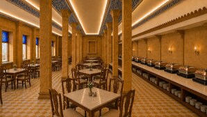 Comedor de hotel con piso a cuadros, mesas y sillas de madera.