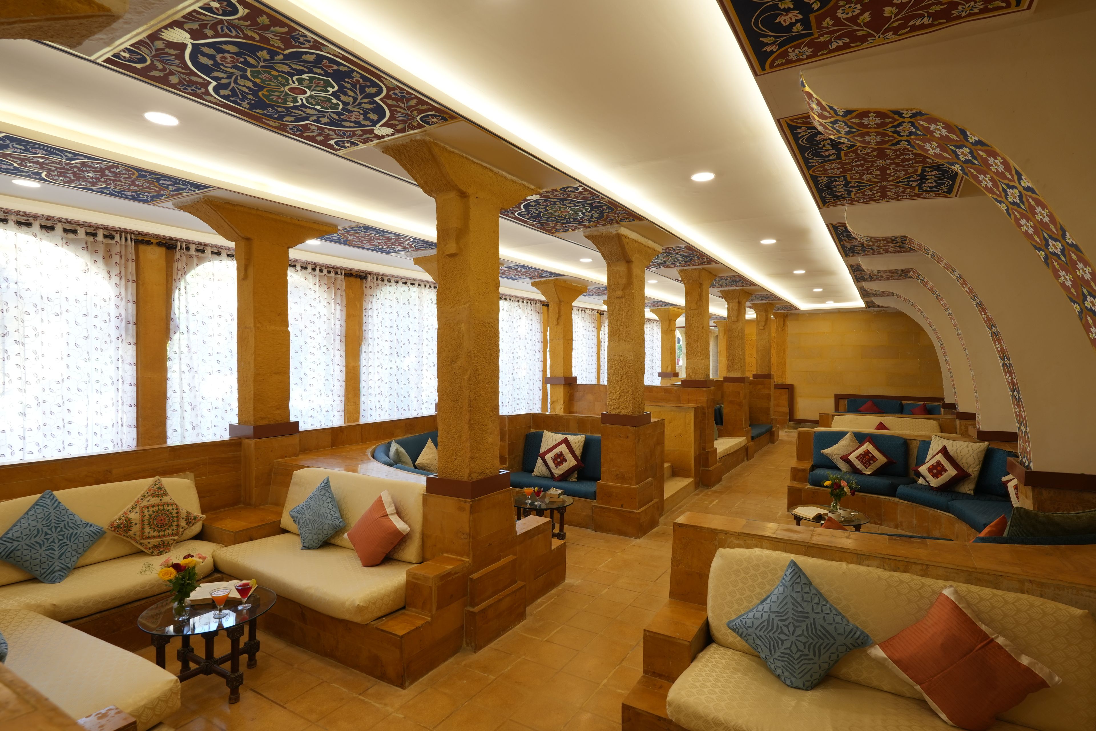A hotel lobby with seating areas, columns, and patterned ceiling designs.