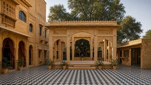 Un patio con suelo a cuadros, pasillos abovedados y plantas en macetas.