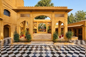 Un patio con piso de mosaicos, arcos y plantas en macetas.