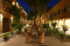 Un patio con mobiliario exterior, rodeado de edificios con arcos y columnas.