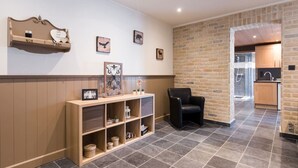 Un hall d’hôtel avec un comptoir d’accueil, un fauteuil en cuir noir et un mur en briques.