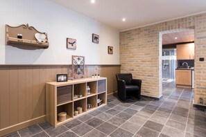 Een hotel lobby met een receptiebalie, een zwarte leren fauteuil en een bakstenen muur.