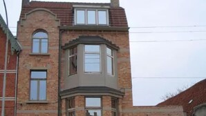Un bâtiment à deux étages doté d’une baie vitrée, d’un garage et d’un petit porche à l’avant.