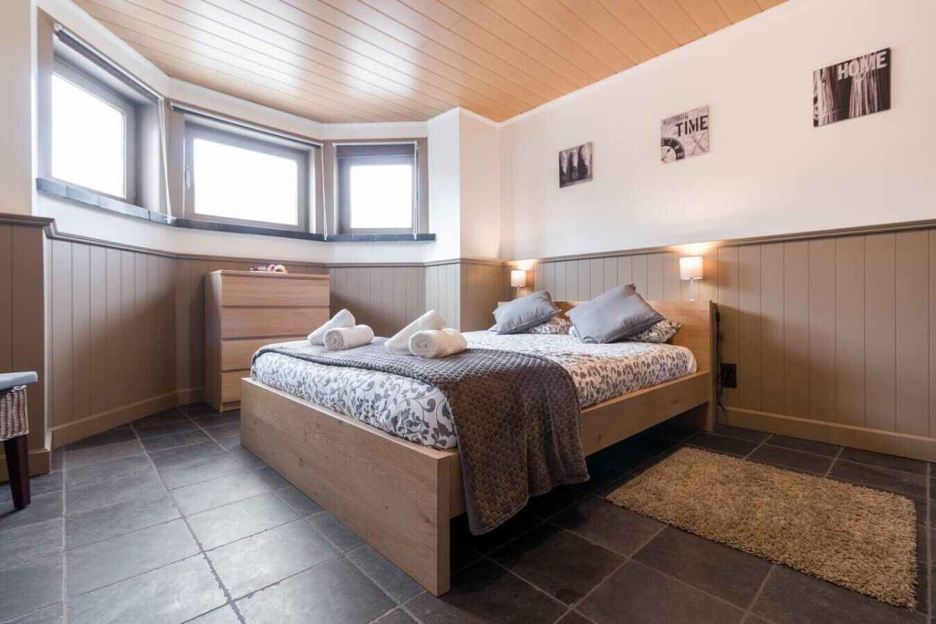 Une chambre à coucher avec un lit, des lampes de chevet, une commode et une fenêtre.