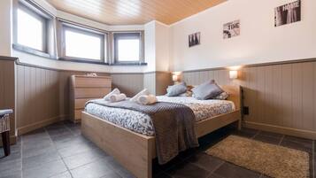 Une chambre à coucher avec un lit, des lampes de chevet, une commode et une fenêtre.
