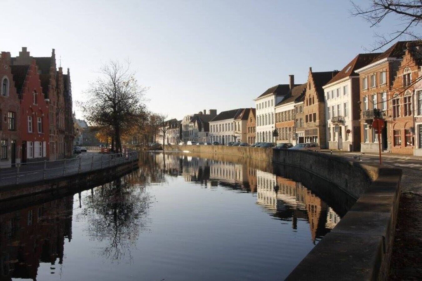 A canal with buildings on either side, a bridge, and a clear sky.