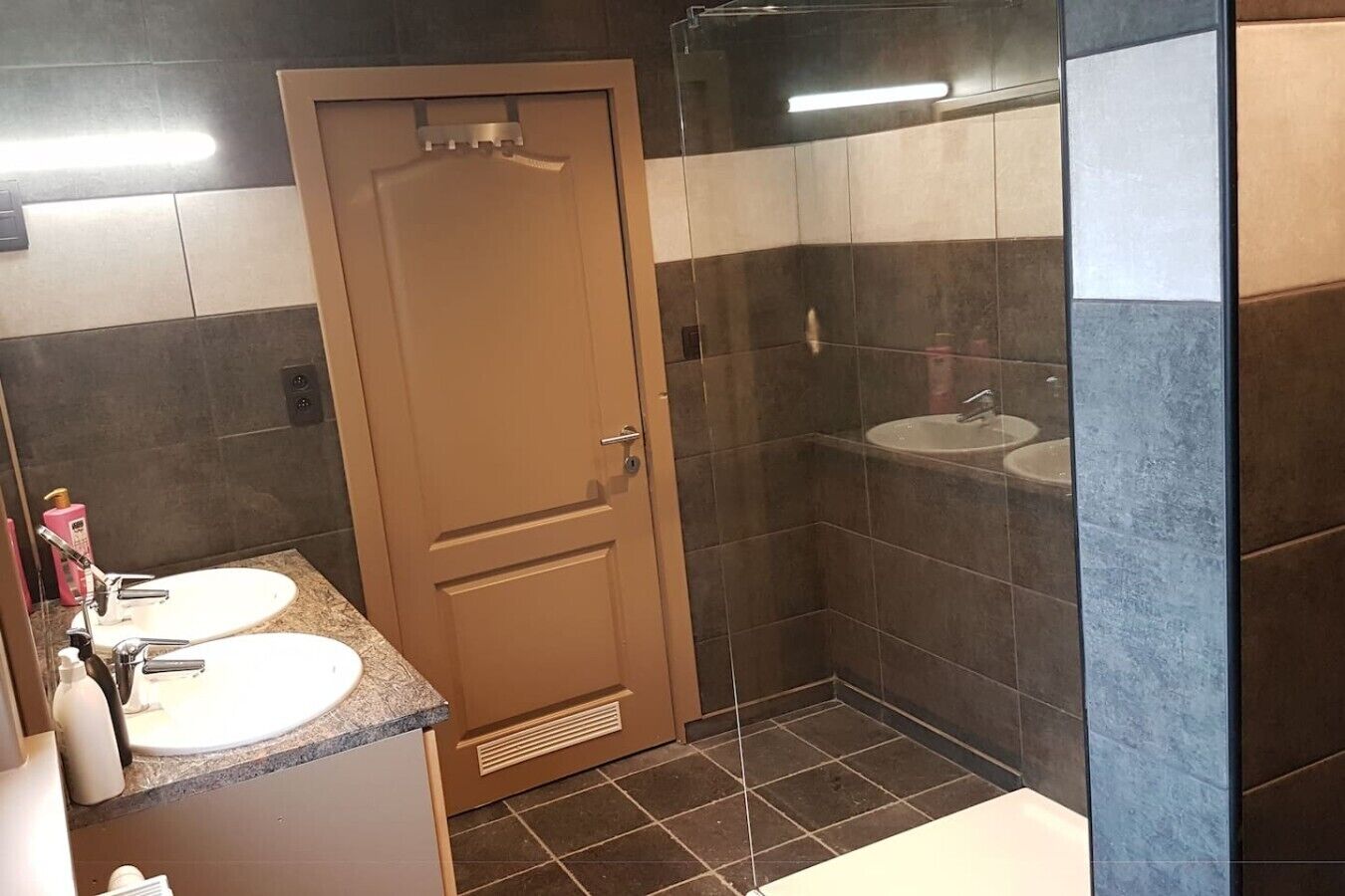 Ein Badezimmer mit zwei Waschbecken, einer Dusche und einer Tür.