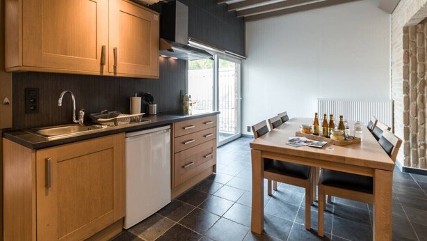 Une cuisine moderne avec des meubles en bois, un lave-vaisselle intégré et un coin repas comprenant une table et des chaises.