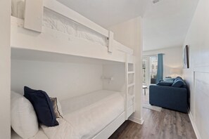 A bunk bed room with a sofa and a window in the adjacent room. - Crystal Beach Condo | Walk to the Gulf (Destin)