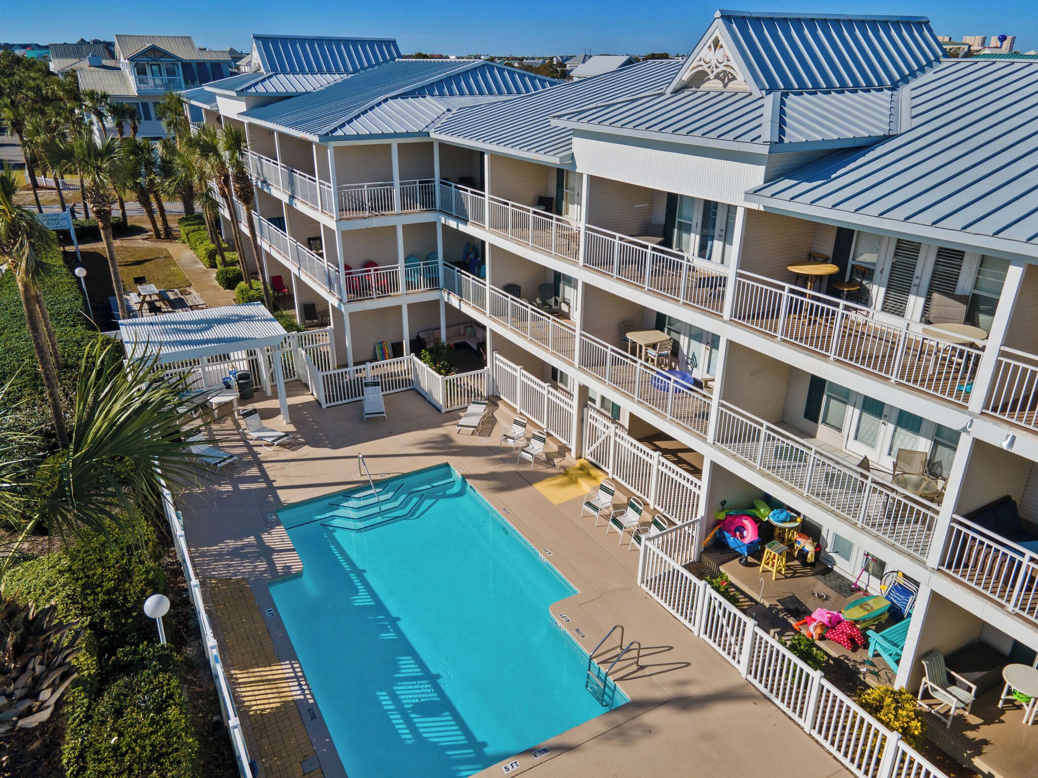 A multi-story hotel with a swimming pool, balconies, and outdoor seating areas.