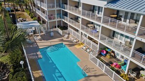Ein mehrstöckiges Hotel mit Schwimmbad, Balkonen und Außenbereichen zum Sitzen.