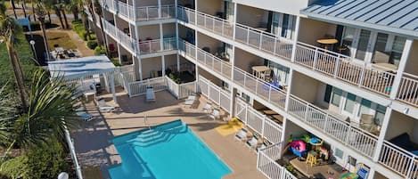 A multi-story hotel with a swimming pool, balconies, and outdoor seating areas.