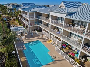 A multi-story hotel with a swimming pool, balconies, and outdoor seating areas. - Crystal Beach Condo | Walk to the Gulf (Destin)