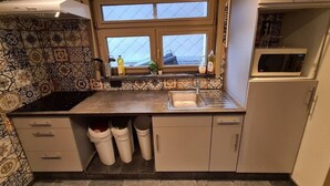 Une cuisine avec des carreaux décoratifs, une fenêtre, un évier et un four à micro-ondes.