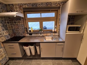 Een keuken met patroontegels, een raam, een spoelbak en een magnetron.