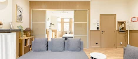 A modern living room with a grey sofa, a small round table, and a wooden floor.