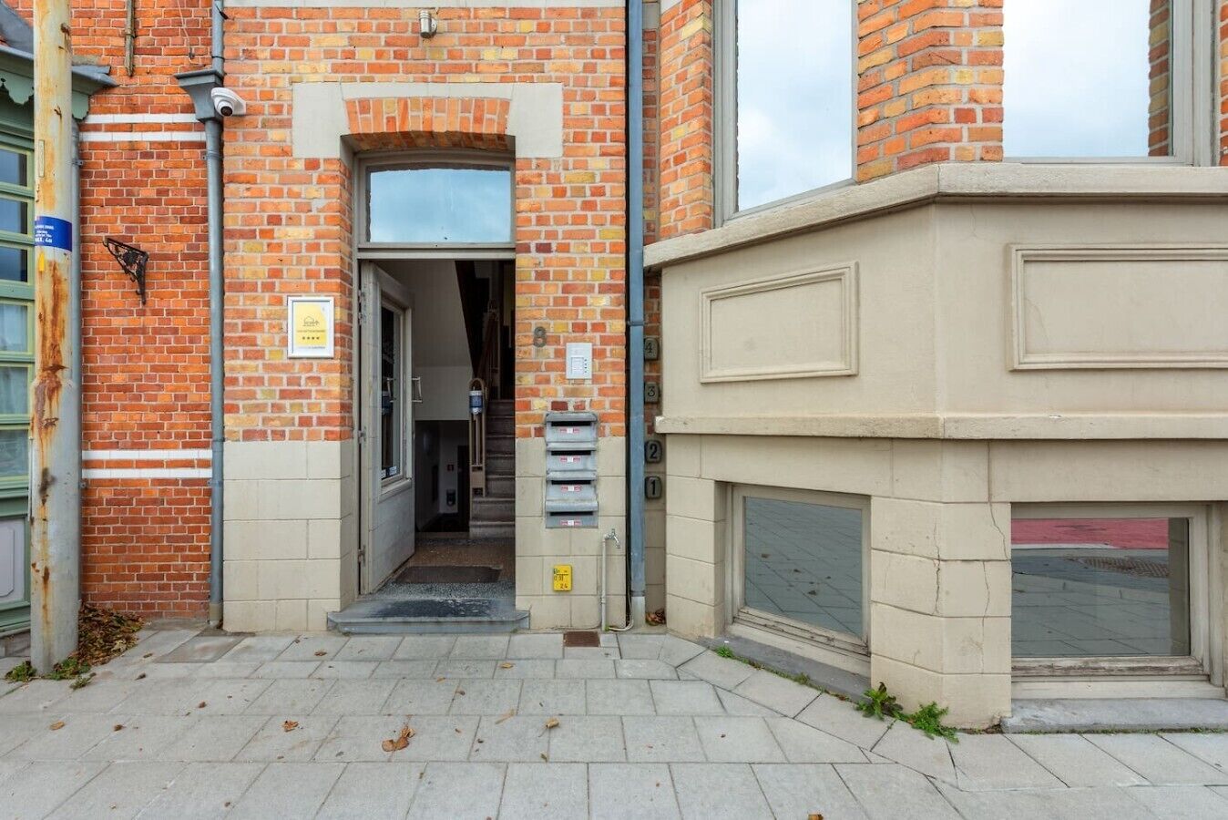 Une entrée d’immeuble avec une façade en briques, une porte et une boîte aux lettres.