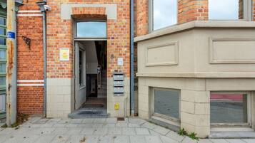 Une entrée d’immeuble avec une façade en briques, une porte et une boîte aux lettres.