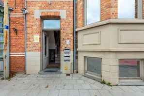 Une entrée d’immeuble avec une façade en briques, une porte et une boîte aux lettres.