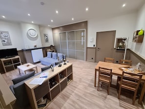 Un salon moderne comprenant un canapé, une table basse et un coin repas avec une table et des chaises en bois.
