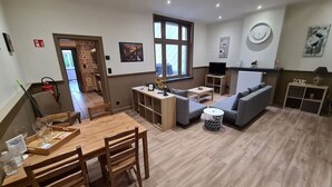 Un vaste espace de vie comprenant une table à manger en bois, des canapés et un téléviseur.