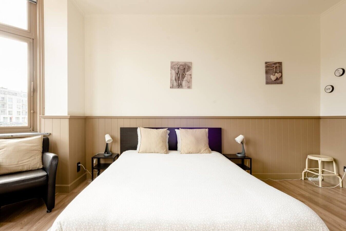 A hotel room with a large bed, two bedside tables, a chair, and a window.