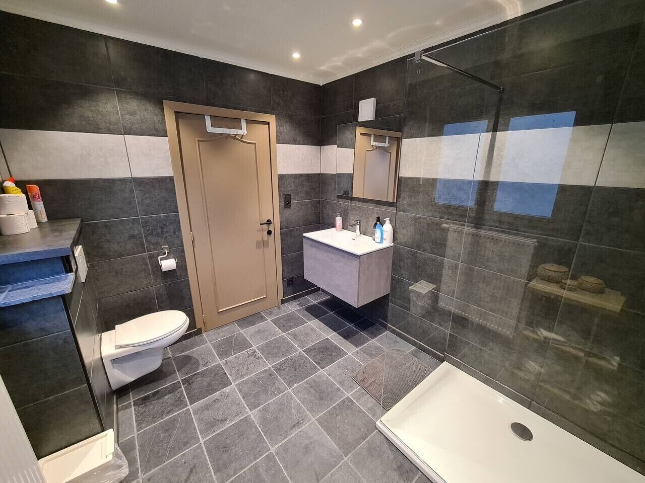 Een moderne badkamer met toilet, wastafel en douche.