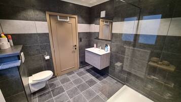 Een moderne badkamer met toilet, wastafel en douche.