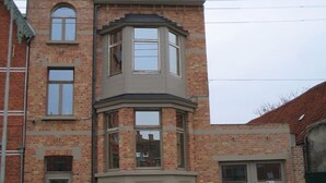 A multi-story building with a bay window and a garage door. - Enjoy Bruges Charming Damse Vaart View Apartment (Brugge, Vlaanderen, BE)
