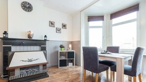 A modern kitchen with a fireplace, wooden flooring, and a dining area with two chairs and a table. - Enjoy Bruges Charming Damse Vaart View Apartment (Brugge, Vlaanderen, BE)