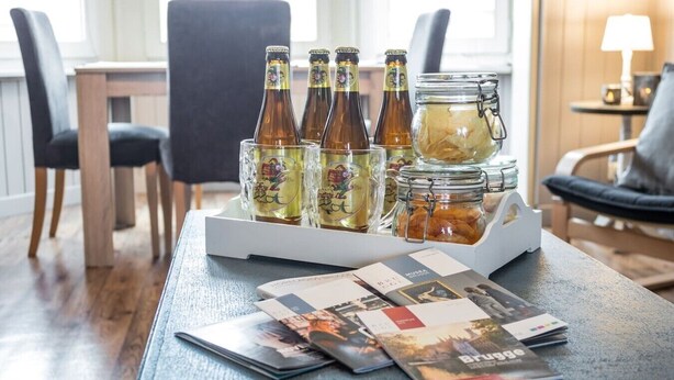 A table with beer bottles, a jar of snacks, and brochures. - Enjoy Bruges Charming Damse Vaart View Apartment (Brugge, Vlaanderen, BE)
