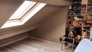 Una habitación con techo inclinado, tragaluces y vistas a un paisaje urbano.