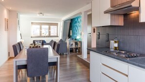 Una cocina moderna con comedor, suelo de madera y vista a través de un ventanal.