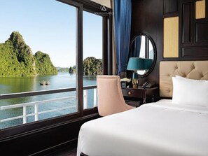 A hotel room with a large window offering a view of a river and forested area. - Lan ha bay luxury cruise (Tuan Chau)
