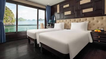 Een hotelkamer met twee bedden, een groot raam met uitzicht op een wateroppervlak en groen, en een donker houten paneel hoofdeinde.