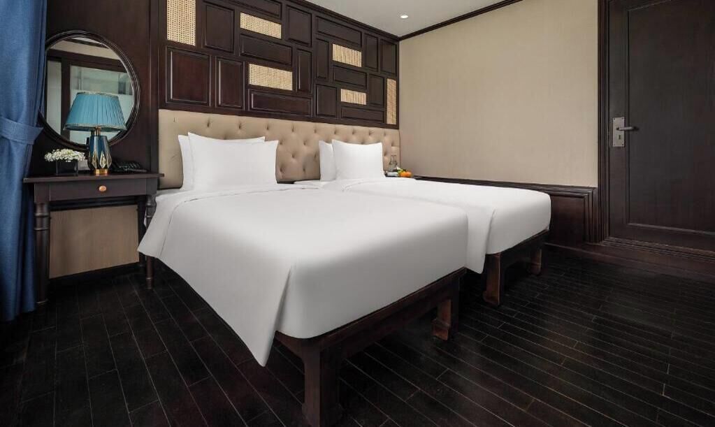 Una habitación de hotel con una cama grande, una mesita de noche con lámpara y un espejo.