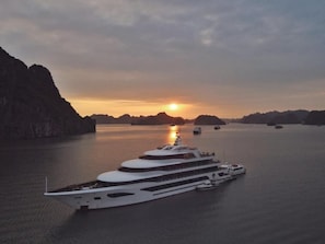 A large white yacht docked in calm waters with a sunset in the background. - Lan ha bay luxury cruise (Tuan Chau)