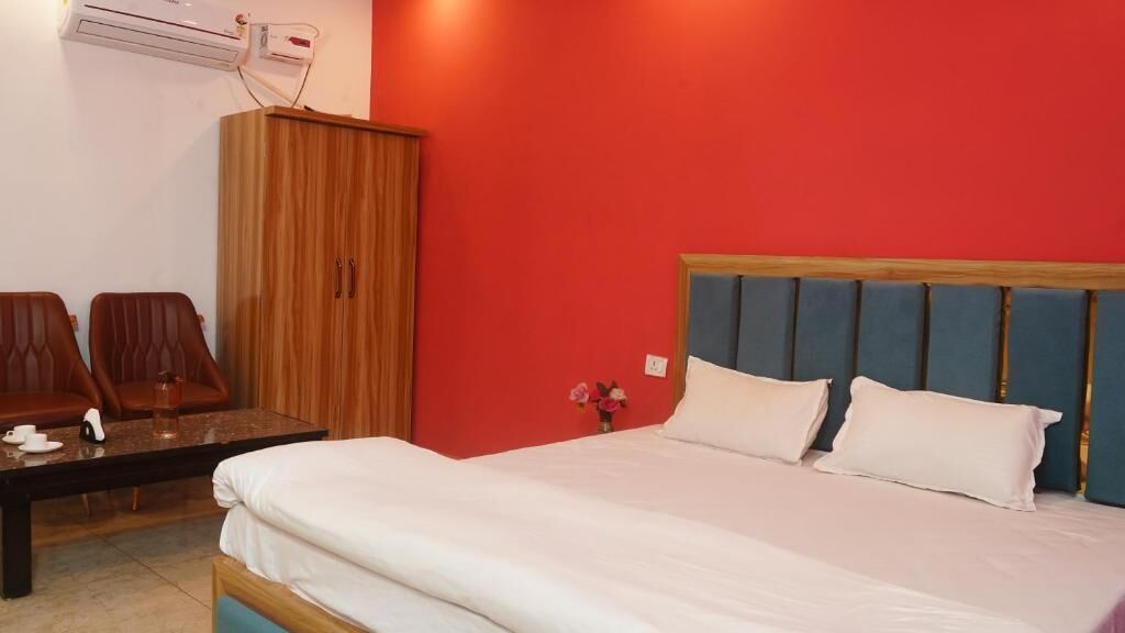A hotel room with a bed, two chairs, a wooden cabinet, and a small table.