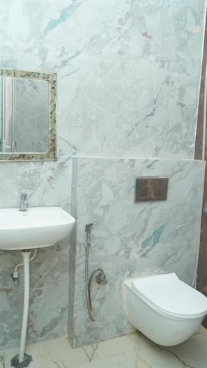 A bathroom with a sink, mirror, and bidet. - SWAGAT GRAND (Bara)